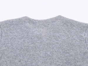 Détail de la texture tricotée gris doux et de l'encolure ronde du manteau chic