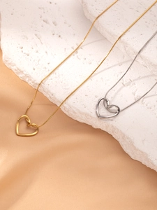 Close-up of gold and silver heart necklaces on stone with sleek snake chains