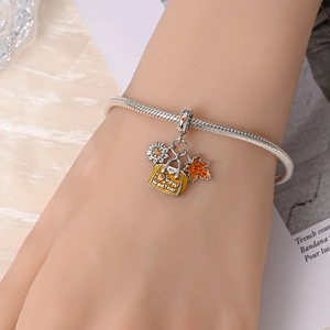 Detailed shot of 925 silver charm with sun, yellow handbag and orange maple leaf