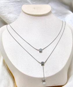 Detail of silver double-layer snake chain necklace with geometric square pendants