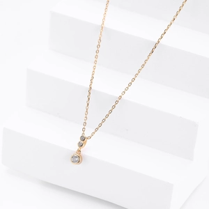 Macro shot of gold necklace featuring three graduated round zircon pendants on minimalist chain