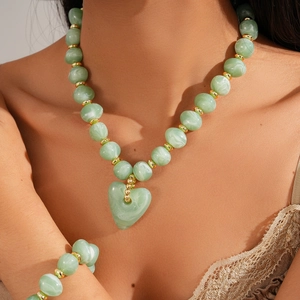 Detail of light green beaded necklace and bracelet set with golden accents and heart pendant