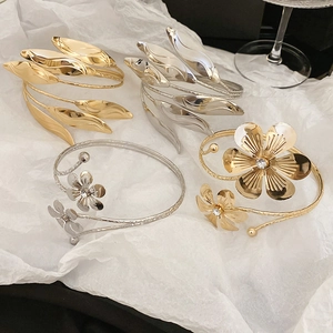 Close-up of layered leaf and floral bangles in gold and silver with zircon accents