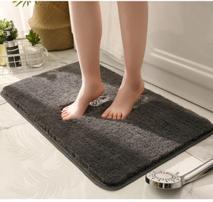 Macro shot of thick grey plush bathroom mat showing water absorption and soft texture