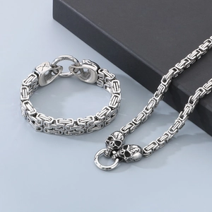 Detailed view of silver stainless steel skull necklace and bracelet set with square weave chain