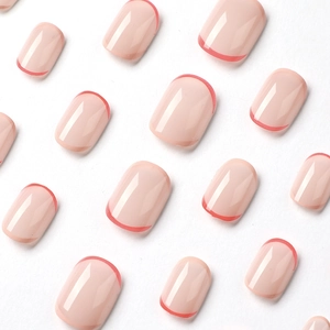 Short round press-on nails with nude pink base and red French tip design on white background