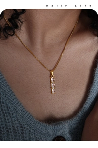 Close-up of golden box chain with a vertical three-stone rectangular crystal pendant