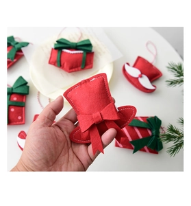 Close-up of handmade red felt Christmas gift bag and hat ornaments with stitching detail