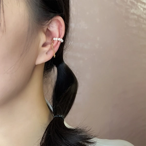 Close-up of gold-plated pearl ear cuff with delicate hanging chain on model