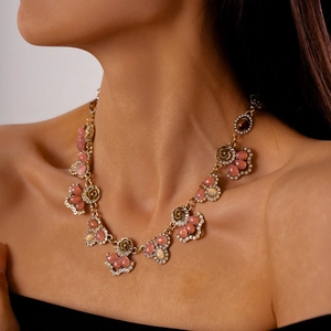 Detailed view of vintage gold necklace with pink resin stones and crystal floral accents