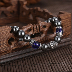 Detail view of retro beaded bracelet with silver Buddha head on a vintage wooden base
