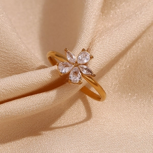 18K gold plated flower ring with five pear-cut zircons on champagne silk fabric