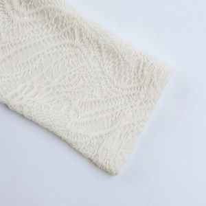 Detailed close-up of cream-white lace fabric texture and hollow-out floral patterns