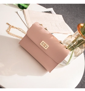 Detail of light pink shoulder bag featuring a gold twist lock and lychee leather texture