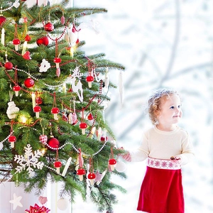 Detail of red and white felt mushroom Christmas ornaments hanging on a festive decorated tree