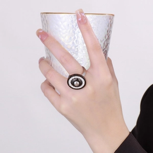 Fashionable black round stainless steel ring with zircon inlays worn by model on a glass