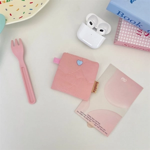 Close-up of pink quilted fabric storage pouch with heart stitching and blue heart charm