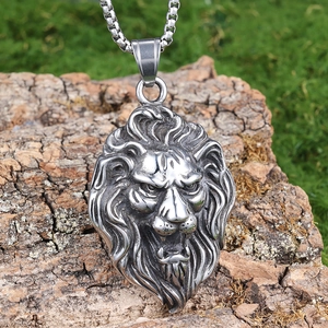 Detailed view of silver lion head pendant on tree bark with blurred green background