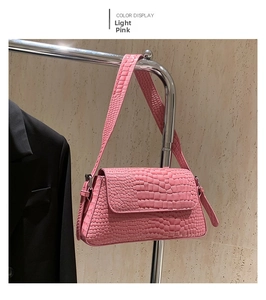 Detail of light pink shoulder bag with glossy crocodile embossed texture on a metal hanger