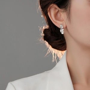 Detail of silver irregular lava metal stud earrings on model for asymmetric style