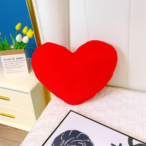 Gros plan du coussin en peluche cœur rouge doux sur literie blanche pour décoration