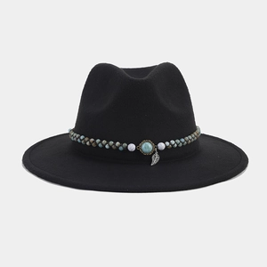 Detalle del sombrero fedora negro con cuentas turquesas bohemias y colgante de hoja plata