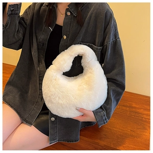 Close-up of white plush crescent handbag held by a model against a warm background