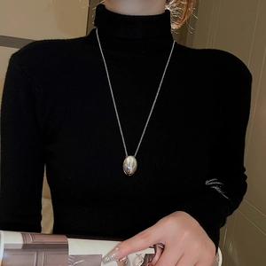 Polished silver geometric oval pendant necklace on a black knit sweater for women