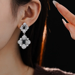 Close-up of geometric flower drop earrings with black zircon on model for a luxury look