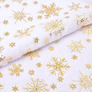 Detail of white faux fur Christmas tree skirt featuring shiny gold foil snowflake patterns