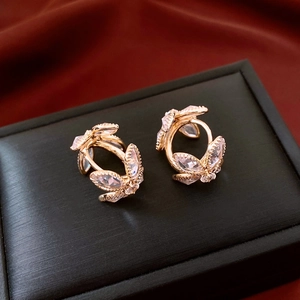 Macro shot of gold leaf earrings with zircon crystals on black velvet display box