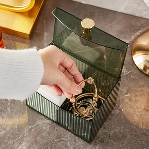 Dark green acrylic cosmetic organizer with gold knob handle on marble desk