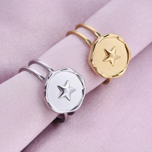 Dual-layer stainless steel star rings in gold and silver finish on soft pink fabric