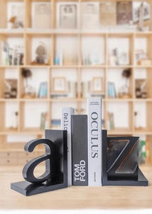 Detail of minimalist black wooden A-Z bookends on a light wooden desk in a modern office