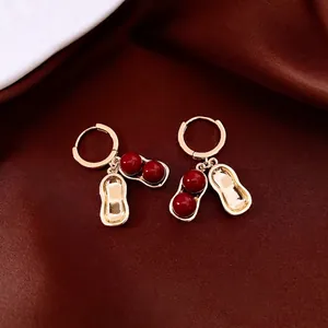 Elegant gold peanut drop earrings with deep red beads on a luxury silk background