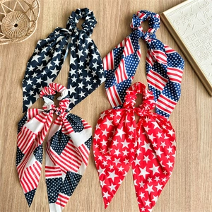 Set of four USA flag pattern hair scrunchies with long ribbons on a wooden surface