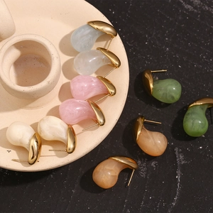 Detailed macro view of vibrant teardrop earrings with gold edges and marble resin textures
