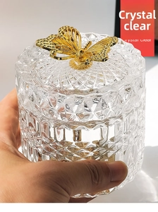 Detail of transparent embossed glass jar featuring a golden butterfly lid handle