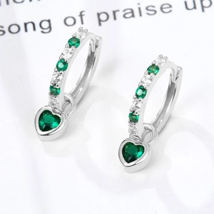 Macro shot of silver heart drop earrings with green zircon stones and sparkling crystals