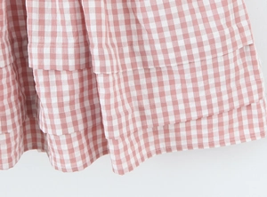 Détail du tissu à carreaux rose et blanc avec volants superposés sur l'ourlet féminin