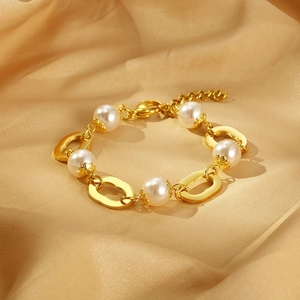 Gros plan du bracelet en or 18 carats avec perles blanches sur tissu en soie dorée