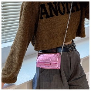 Pink crocodile pattern chain bag detail with glossy finish shown on shoulder