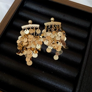 Detailed view of golden sequin tassel earrings on a premium black velvet jewelry tray
