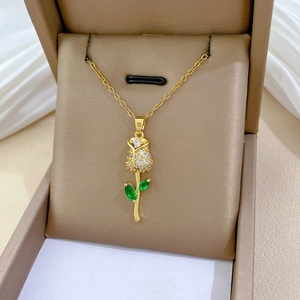 Close-up of rose pendant with pavé diamonds and emerald green leaves on gold chain