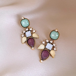 Detail of vintage multicolor resin earrings with rhinestones on champagne silk fabric