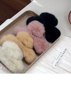 Detailed view of plush faux fur claw clips in black, pink, beige and white colors