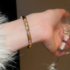 Close-up of a gold bracelet featuring three marquise-cut pink zircons on a white sleeve