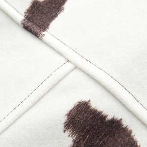 Macro shot of faux fur fabric showing brown cow print pattern and durable cross-stitch seams