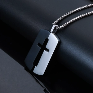 Gros plan du pendentif croix bicolore noir et argent en acier inoxydable sur fond cuir