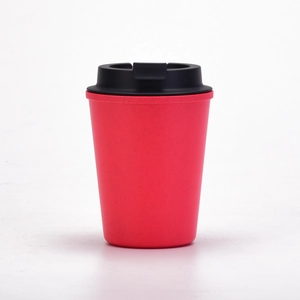 Detail of red wheat straw coffee cup with a black spill-proof lid on a white background